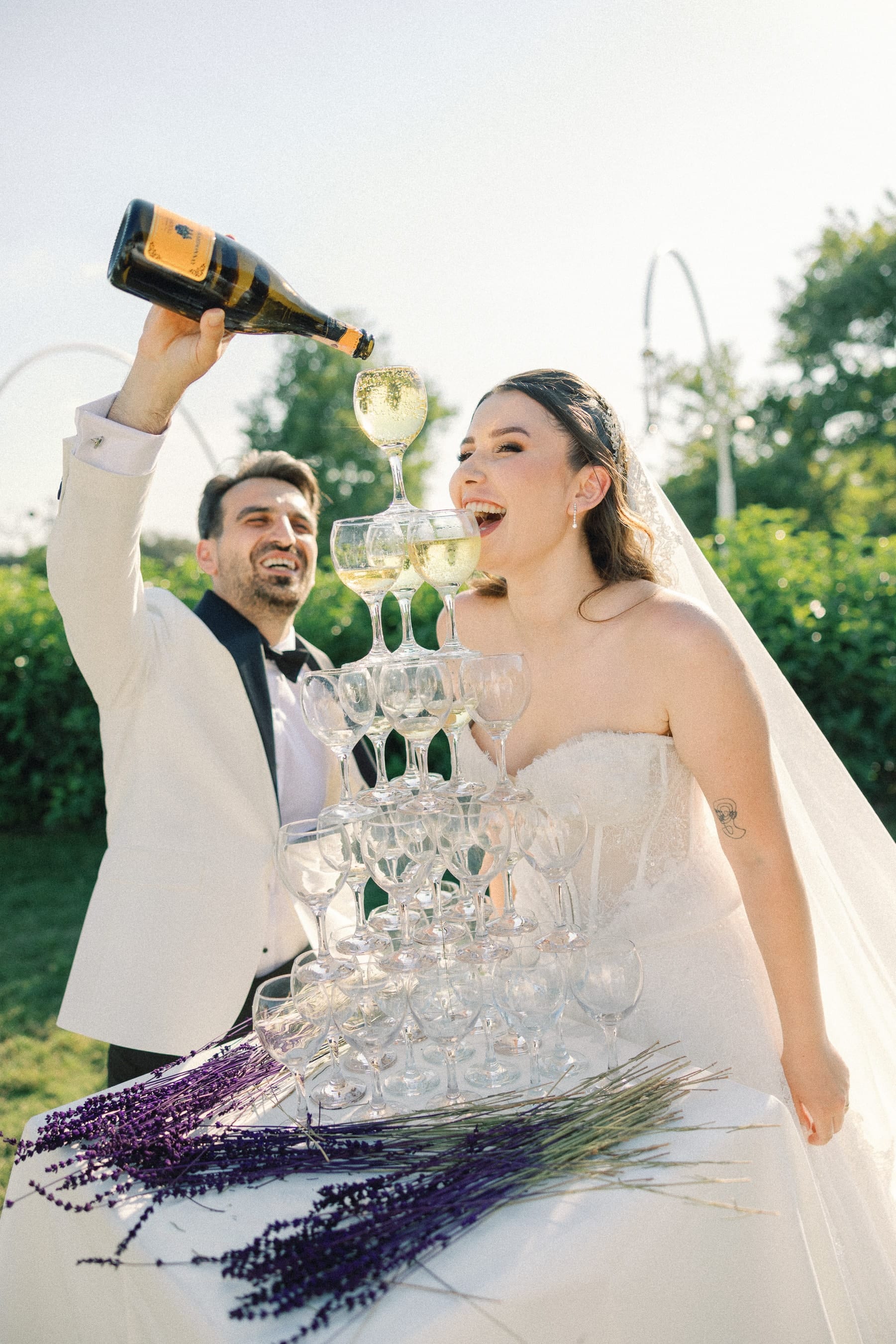 Şampanya kulesine içecek dolduran gelin ve damat