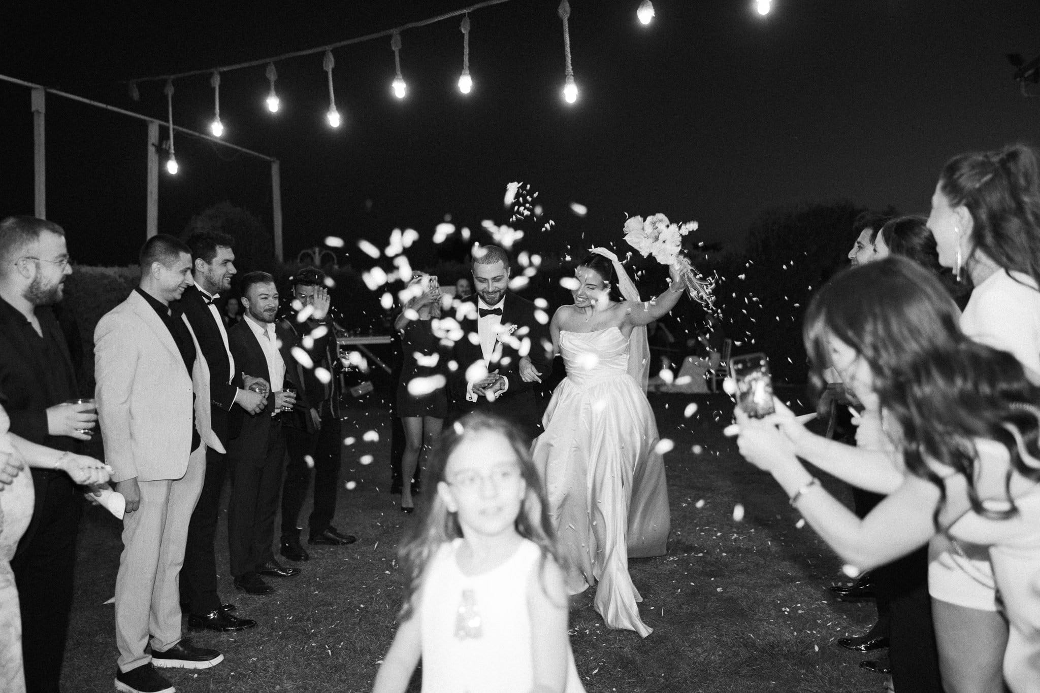 Gece ip fenerlerin altında konfetiler arasından geçen gelin ve damat