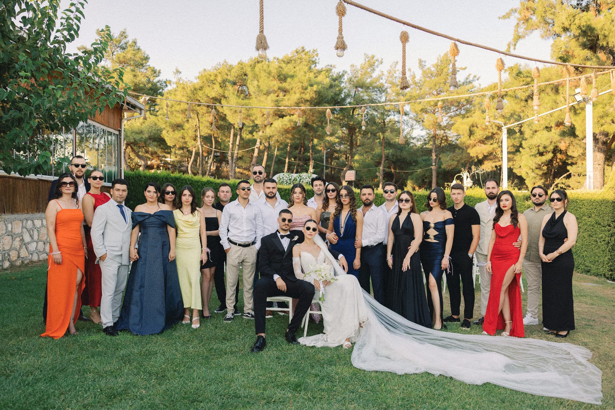 Bahçe düğününde gün batımında davetlilerle birlikte gelin ve damat