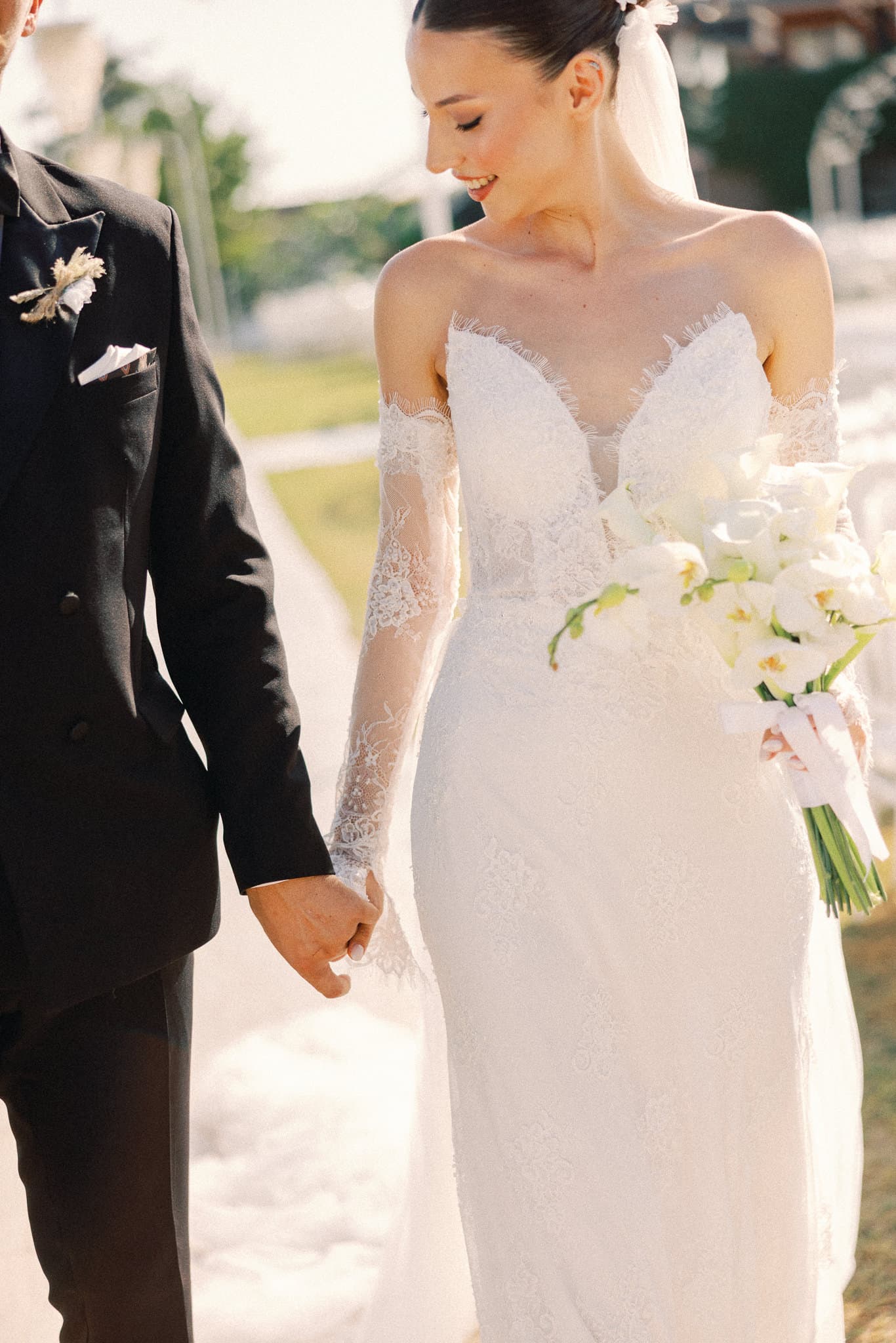 El ele yürüyen gelin ve damat, gelinin elinde beyaz orkide buketi