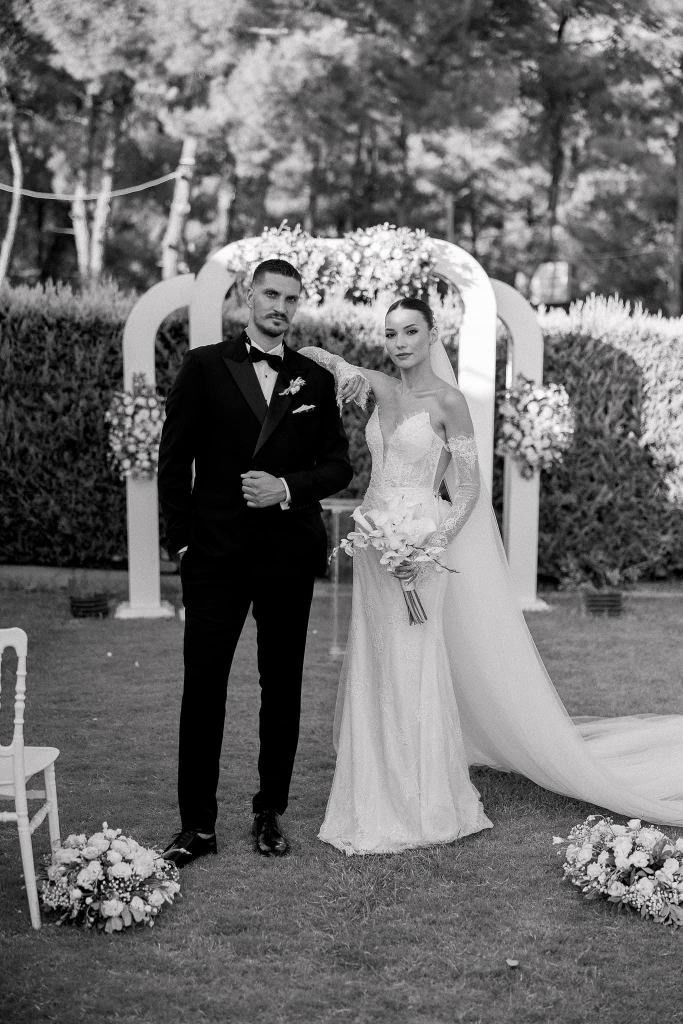 Bahçede çiçekli kemerin önünde tören sırasında gelin ve damat
